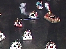 An overhead shot of the Show Down carts in battle, with a beam of liught coming from General Tani's cart towards Takeshi's cart which has smoke bellowing from it.