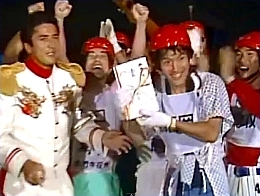 A winner hold up his award surrounded by fellow contestants and General Tani